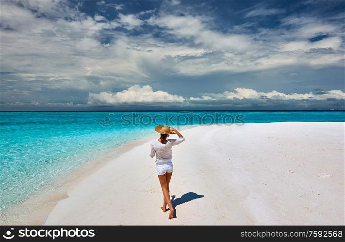 Woman with sun hat on tropical beach at Maldives
