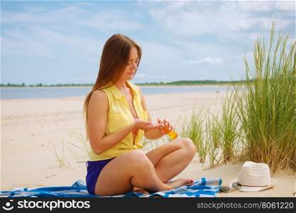 Woman with sun oil.. Skin protection in summer. Woman on beach using sun oil. Young beauty girl taking sunbath on sunny day. Holidays time.