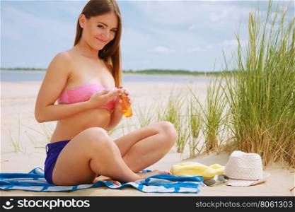 Woman with sun oil.. Skin protection in summer. Woman on beach using sun oil. Young beauty girl taking sunbath on sunny day. Holidays time.