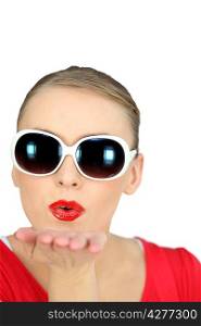 Woman with sunglasses blowing kisses on white background