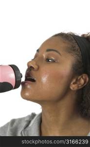 Woman with sweaty face having a refreshing drink after her workout