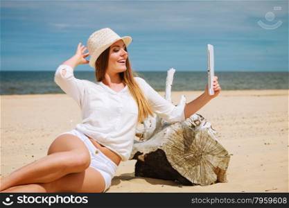 Woman with tablet on beach taking self selfie photo. Technological resting