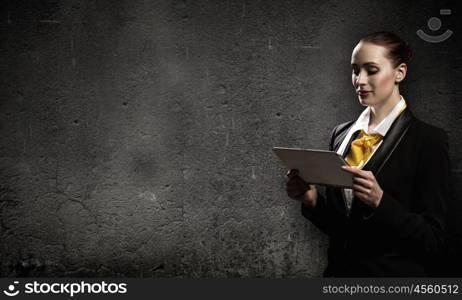 Woman with tablet pc. Young pretty businesswoman against grey background using tablet pc