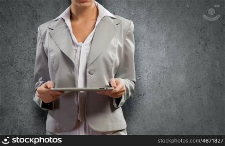 Woman with tablet pc. Young pretty businesswoman against grey background using tablet pc