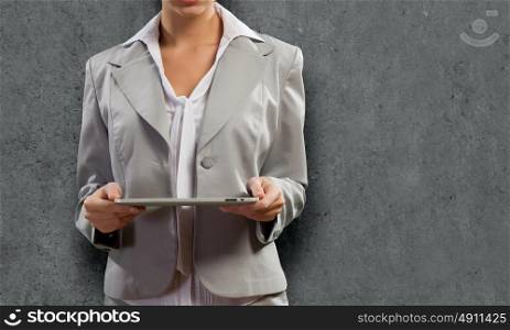 Woman with tablet pc. Young pretty businesswoman against grey background using tablet pc