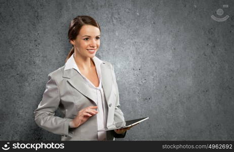 Woman with tablet pc. Young pretty businesswoman against grey background using tablet pc