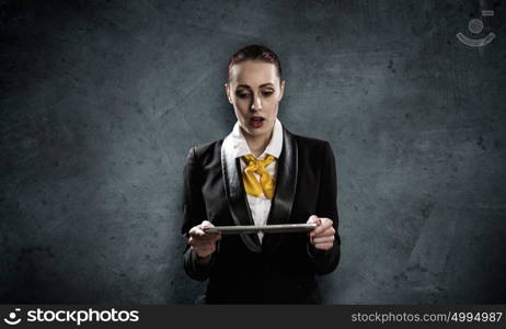 Woman with tablet pc. Young pretty businesswoman against grey background using tablet pc