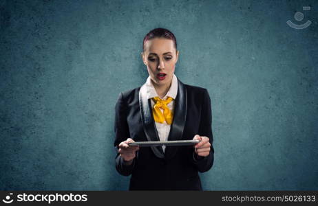 Woman with tablet pc. Young pretty businesswoman against grey background using tablet pc