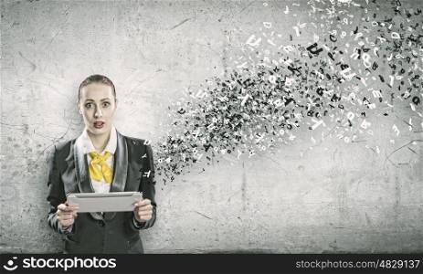 Woman with tablet pc. Young shocked woman holding tablet pc in hands and letters flying around