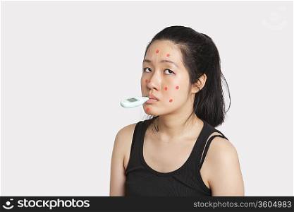 Woman with thermometer in mouth suffering from measles