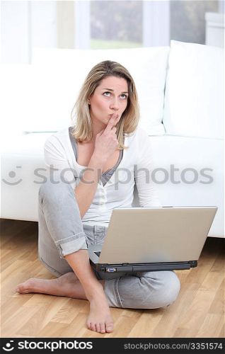 Woman with thoughtful look using laptop computer