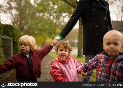 Woman with three children walking along pavement