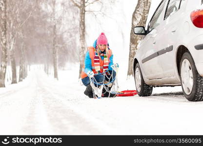 Woman with tire chains car snow breakdown smiling fixing winter