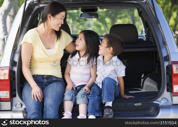 Woman with two children sitting in back of van smiling