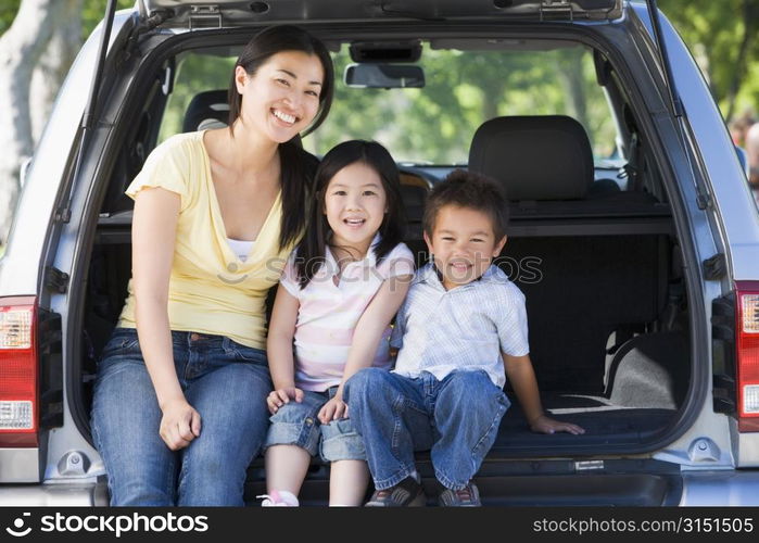 Woman with two children sitting in back of van smiling