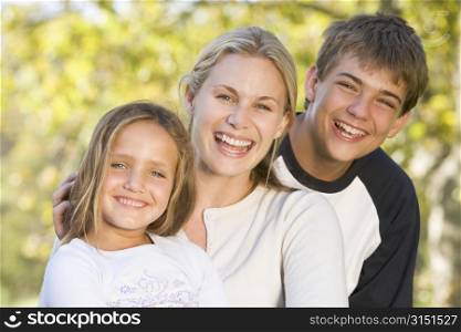 Woman with two young children outdoors smiling