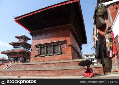 Woman with umbrell on the steps of hindu temple in Khatmandu, Nepal