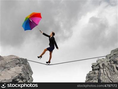 Woman with umbrella. Young businesswoman walking on rope above gap with colorful umbrella