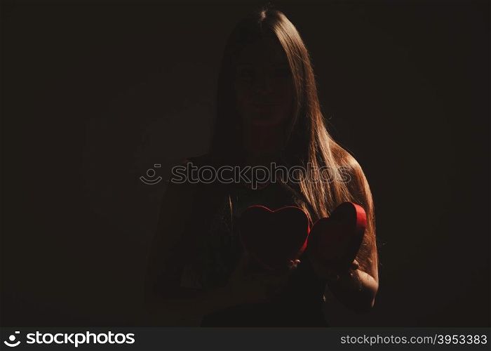 Woman with valentines box. Valentine day. Woman in black holding heart box gift present. Elegant attractive model with valentines symbol sign. Studio shot.