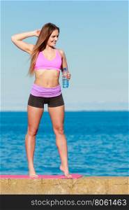 Woman with water after workout. Health and body care idea. Sporty fit attractive woman with bottle of water after exercising workout outdoor.