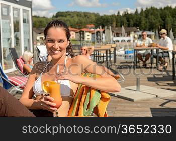 Woman with wet hair drinking cocktail sitting at beach bar