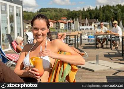 Woman with wet hair drinking cocktail sitting at beach bar