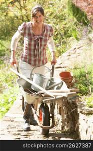 Woman With Wheelbarrow Working Outdoors In Garden