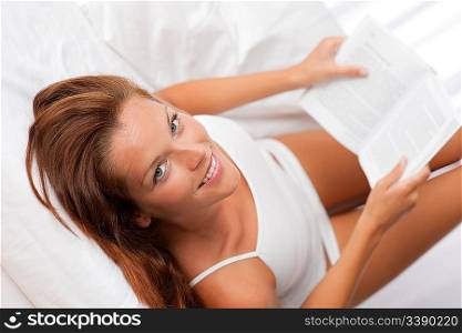 Woman with white book lying in bed