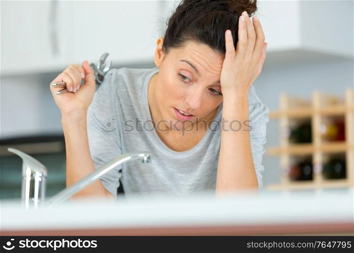 woman with wrench struggling to repair her sink