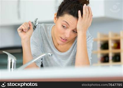 woman with wrench struggling to repair her sink