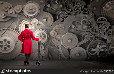 Woman with wrench. Young woman in red coat fixing mechanism with wrench