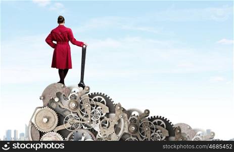 Woman with wrench. Young woman in red coat fixing mechanism with wrench