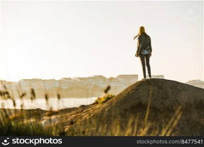 Woman with yellow cap over the cliff seeing the beach