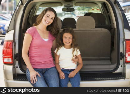 Woman with young girl sitting in back of van smiling