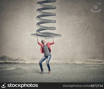 Woman withstand pressure. Young woman in red jacket resisting big metal spring