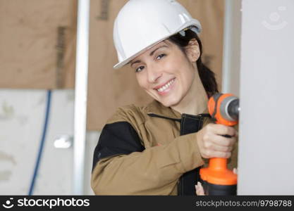 woman worker drilling something at construction site