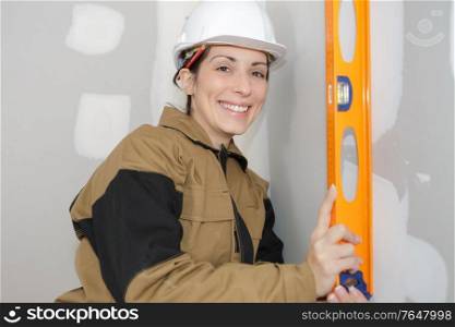 woman worker leaning a spirit level on the wall