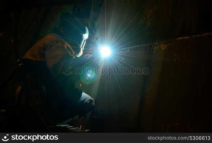 Woman worker welding inside of shipyard