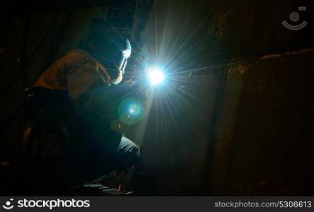 Woman worker welding inside of shipyard