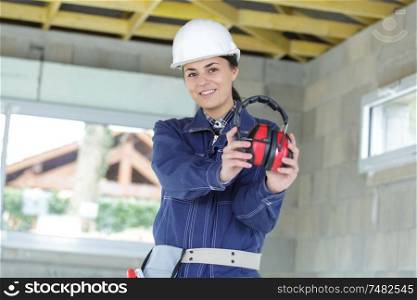 woman worker with protective helmet showing headphone