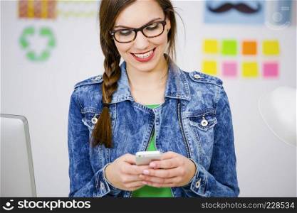 Woman working at desk In a creative office and texting a message 