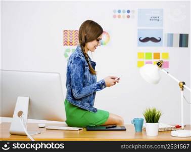 Woman working at desk In a creative office and texting a message