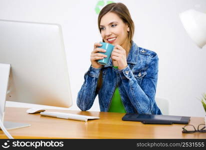 Woman working at desk In a creative office holding a cup