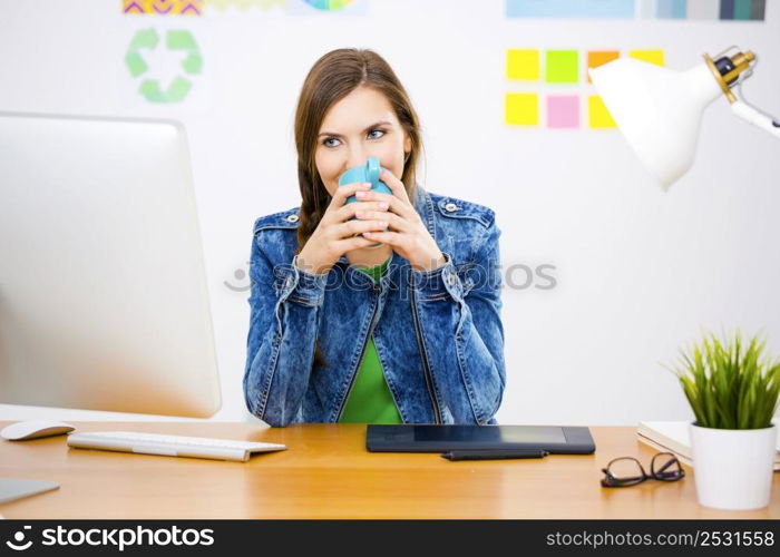 Woman working at desk In a creative office holding a cup