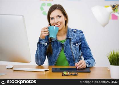 Woman working at desk In a creative office holding a cup