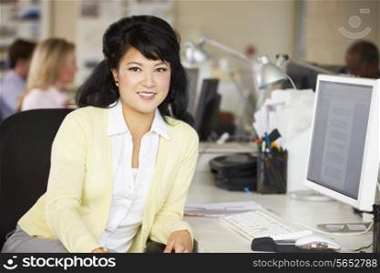 Woman Working At Desk In Busy Creative Office