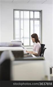 Woman working at desk in office, side view