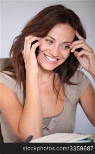 Woman working at home on laptop computer with telephone