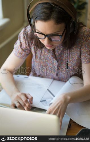 Woman working at home with laptop and architecture plan