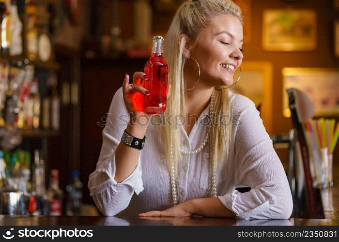 Woman working at the bar counter, holding red bottle lemonade. Woman working at the bar counter